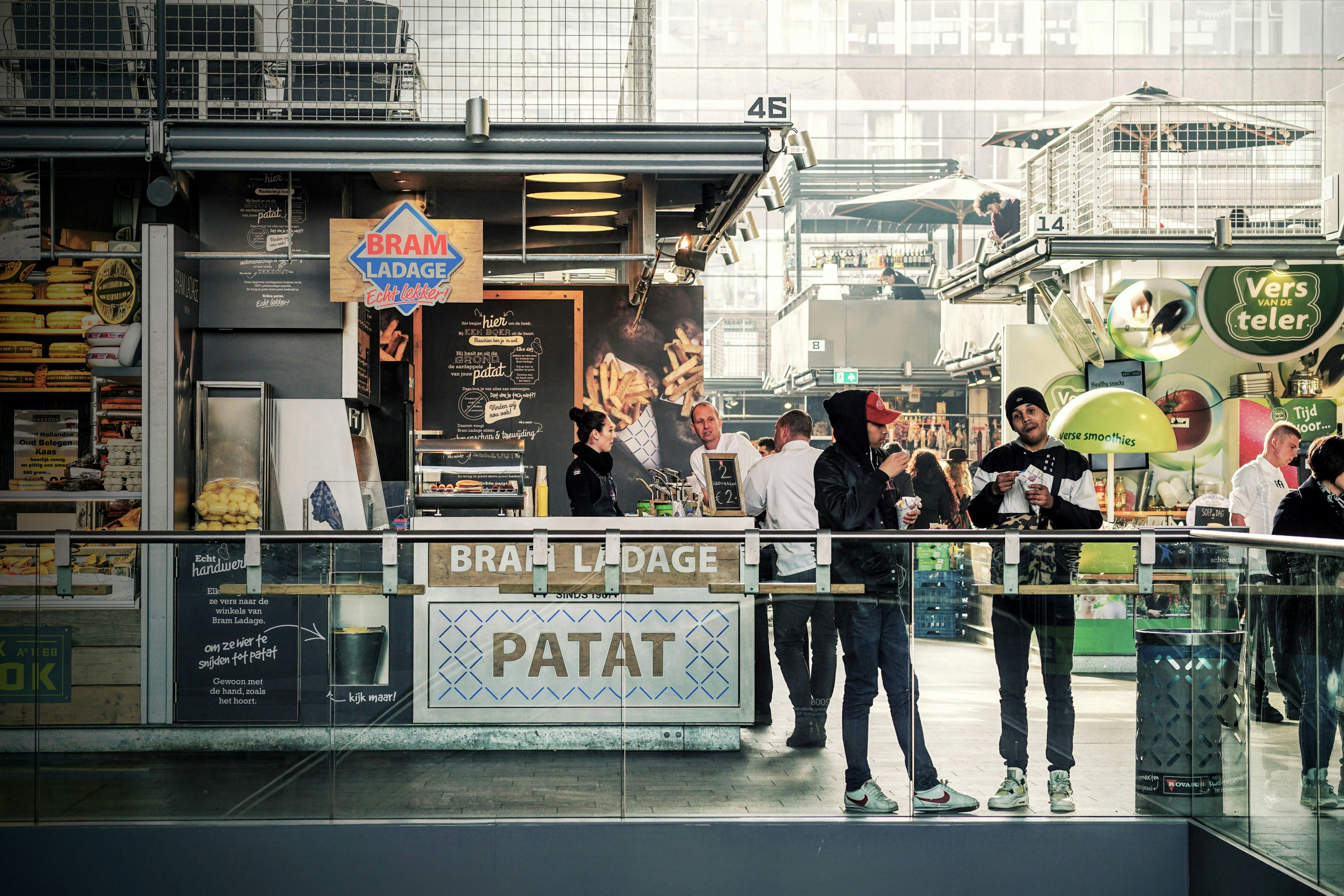 People enjoying street food at a bustling indoor market in Rotterdam, Netherlands.