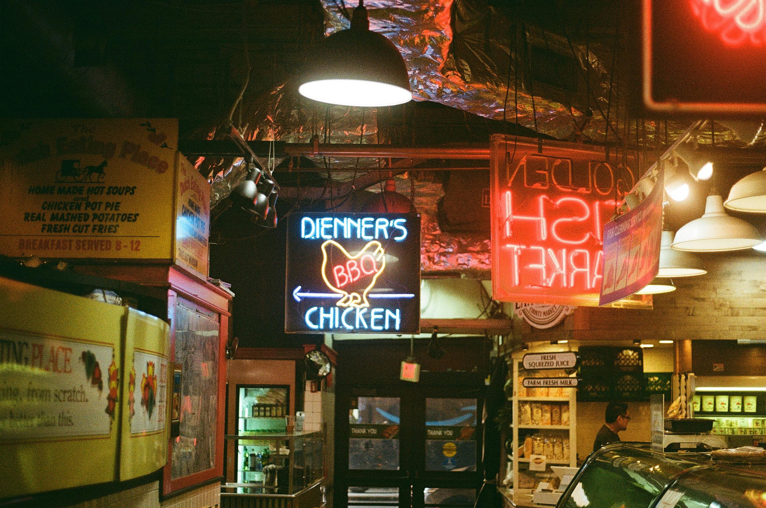 Vibrant neon signs illuminate a bustling Philadelphia market showcasing local cuisine.