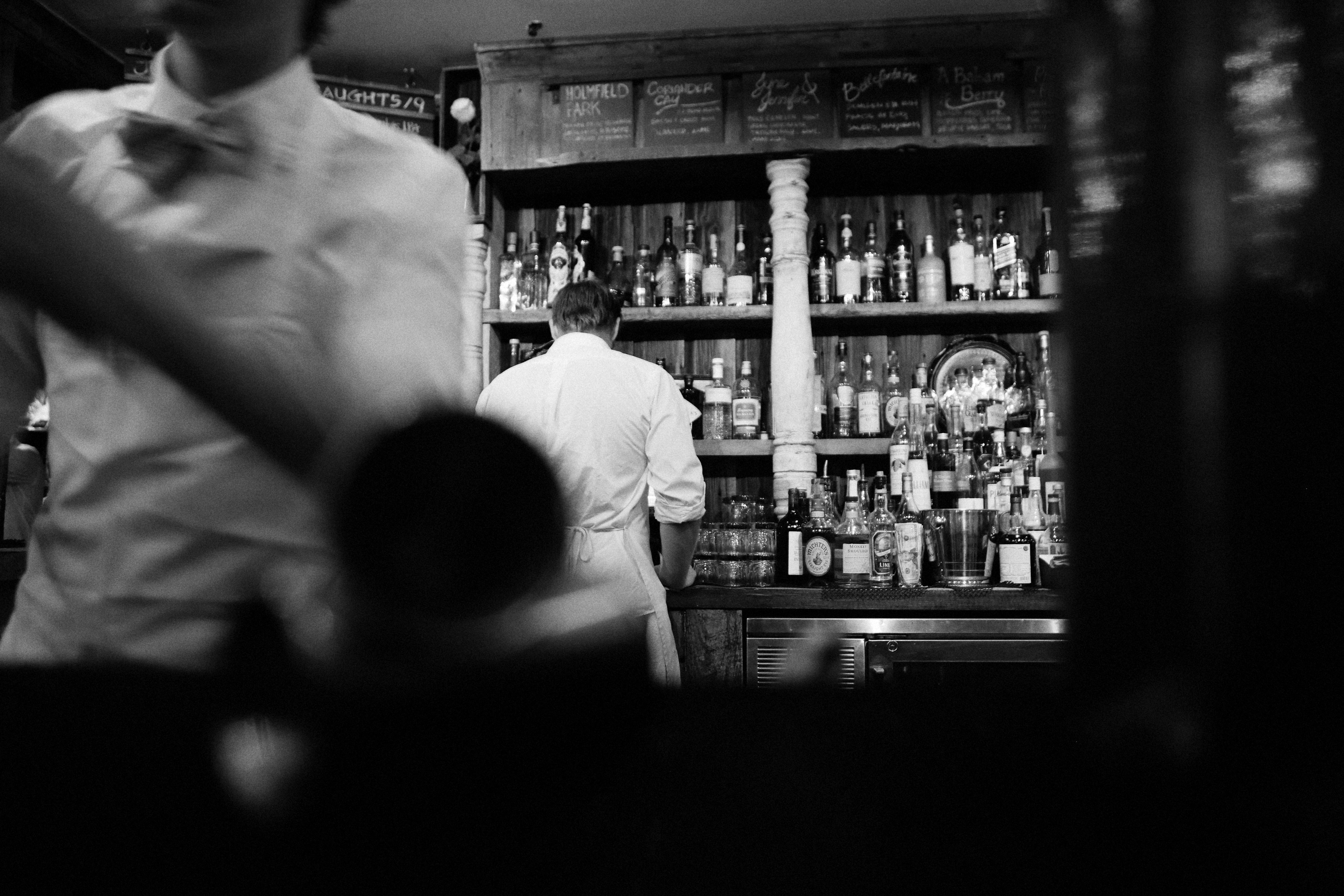 A black and white photo capturing bartenders at work in a vintage bar setting.